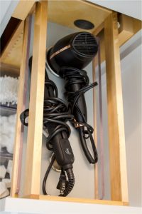 CE-Bath-Gallery12 Hair dryers and towels are stored in a wooden cabinet.