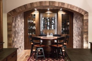 CE-Custom-Gallery10 A wine cellar with custom cabinets for storage and a table and chairs for tasting.